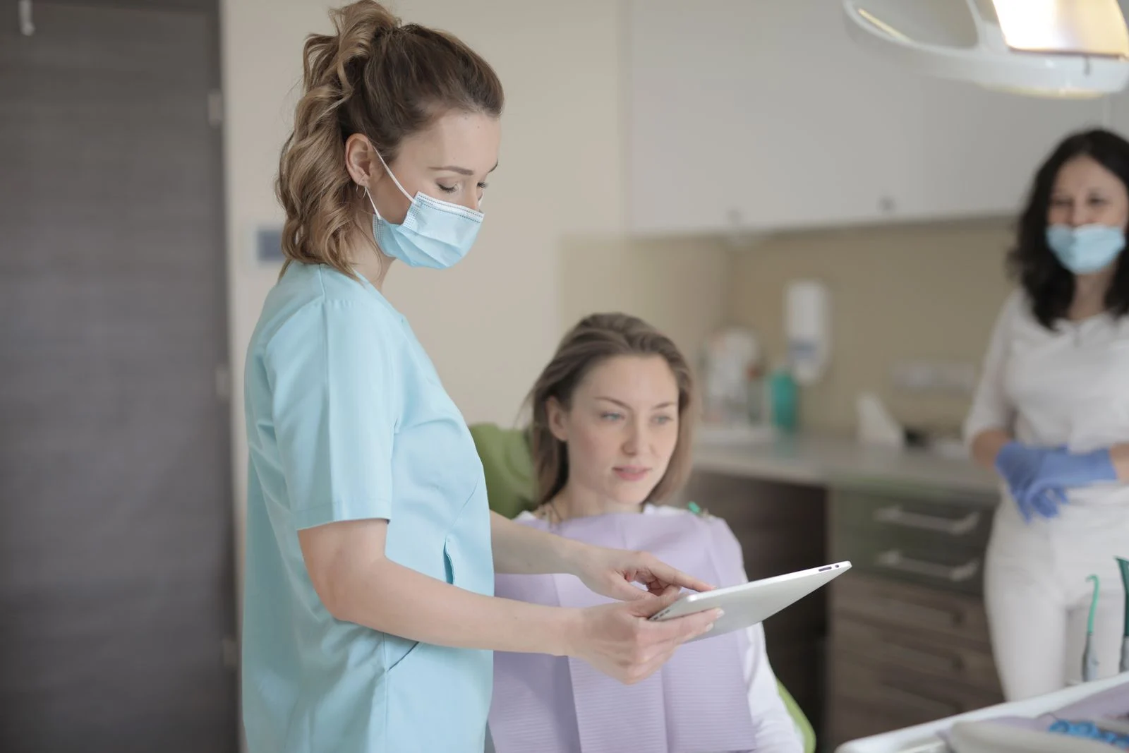 Dentist explaining a treatment plan on a tablet to a seated patient