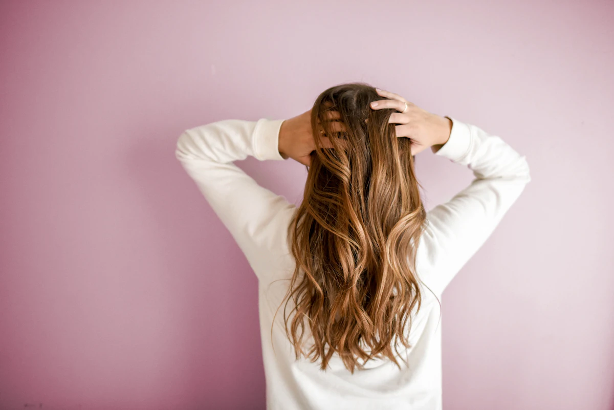 Woman with long wavy hair against a soft pink wall